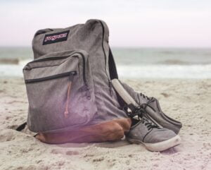 black and red nike backpack on brown sand near body of water during daytime