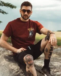 man sits on stone near grass field during daytime
